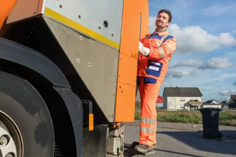 dumpster contractor riding at the back of disposal vehicle